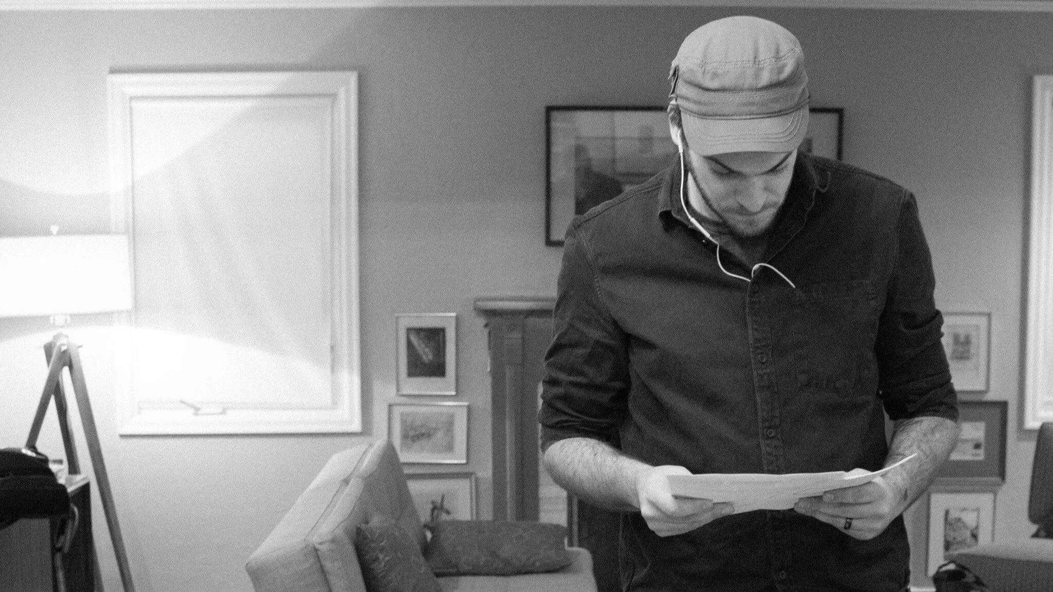 A man wearing a cap and earphones looking down at a box or tray on a table.