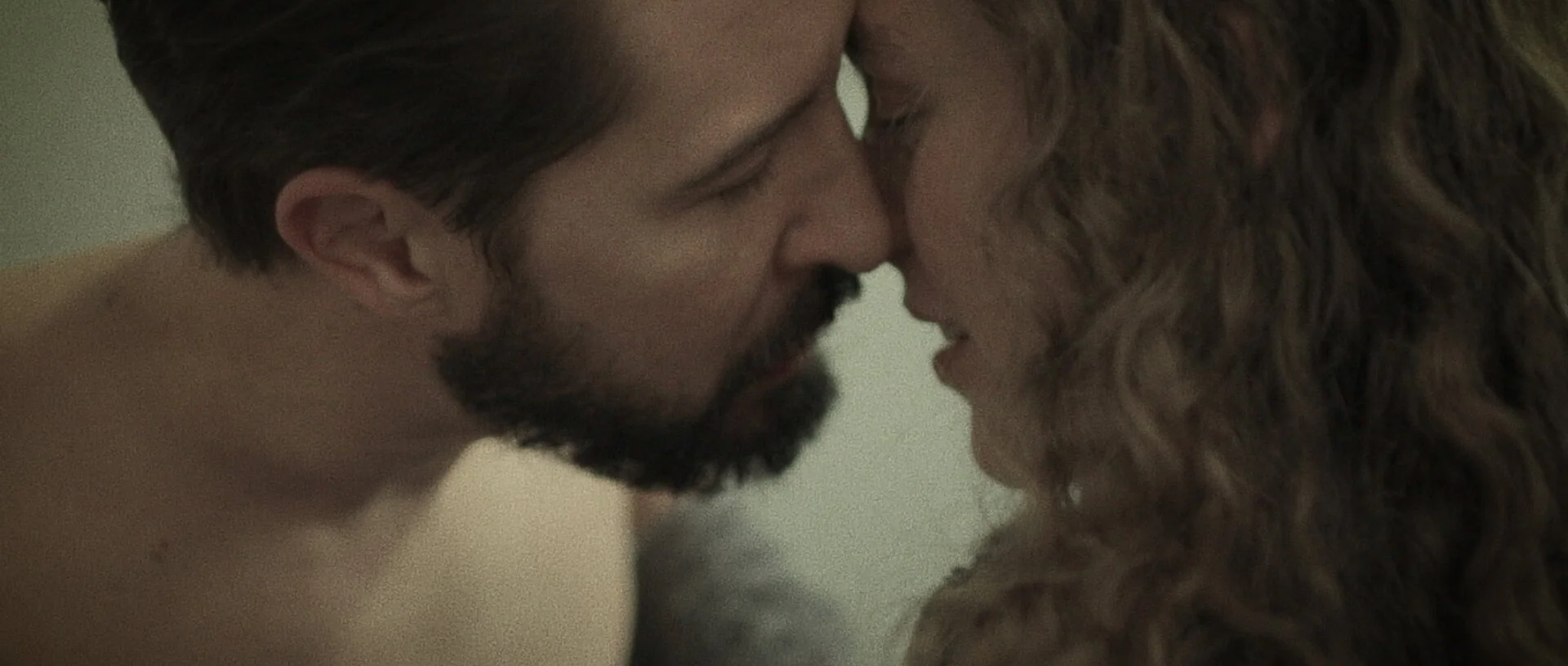 Two people, one man and one woman, with their foreheads touching, eyes closed, sharing an intimate moment.