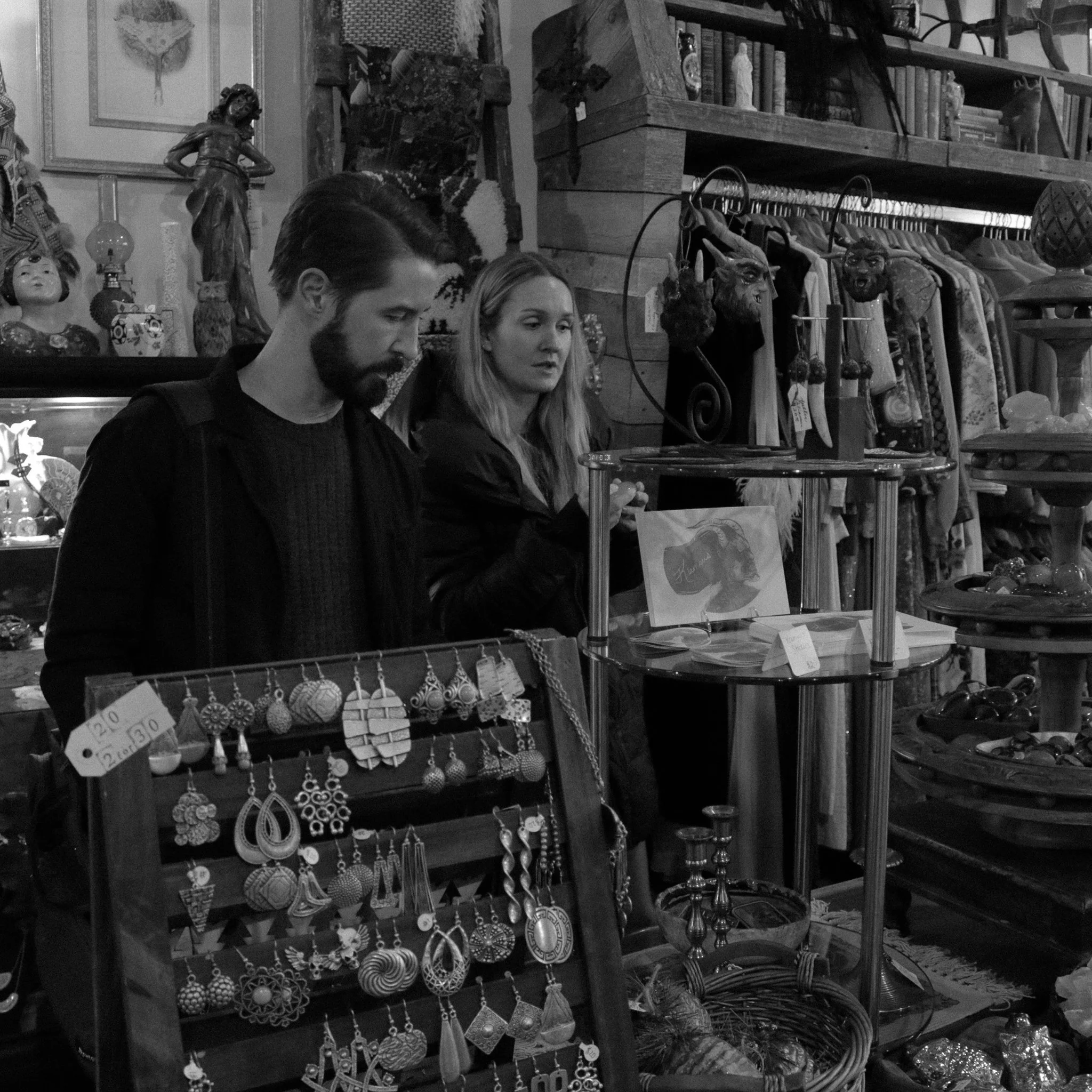 People shopping at a store with jewelry and decorative items displayed on shelves and racks.