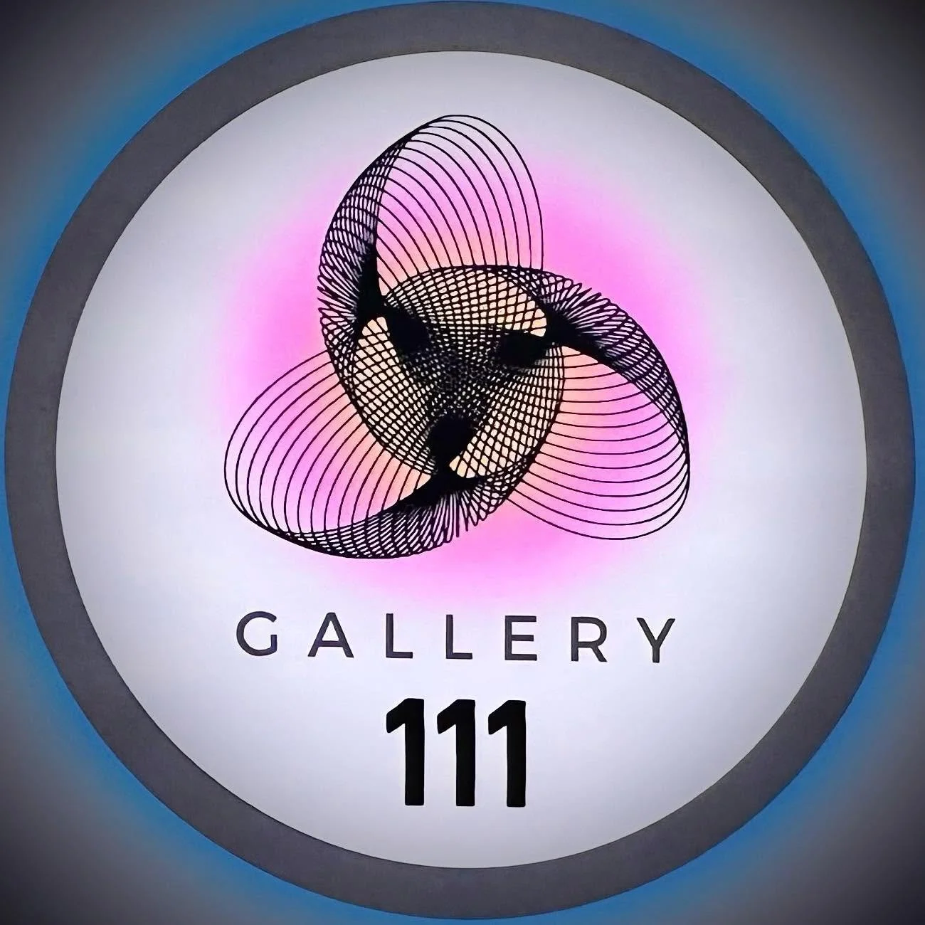 A circular logo with the word "GALLERY" and the number "111" underneath. The logo features a black geometric abstract design resembling interconnected spirals, set against a white background with a pink hue in the center, surrounded by a gradient border from dark gray to blue.