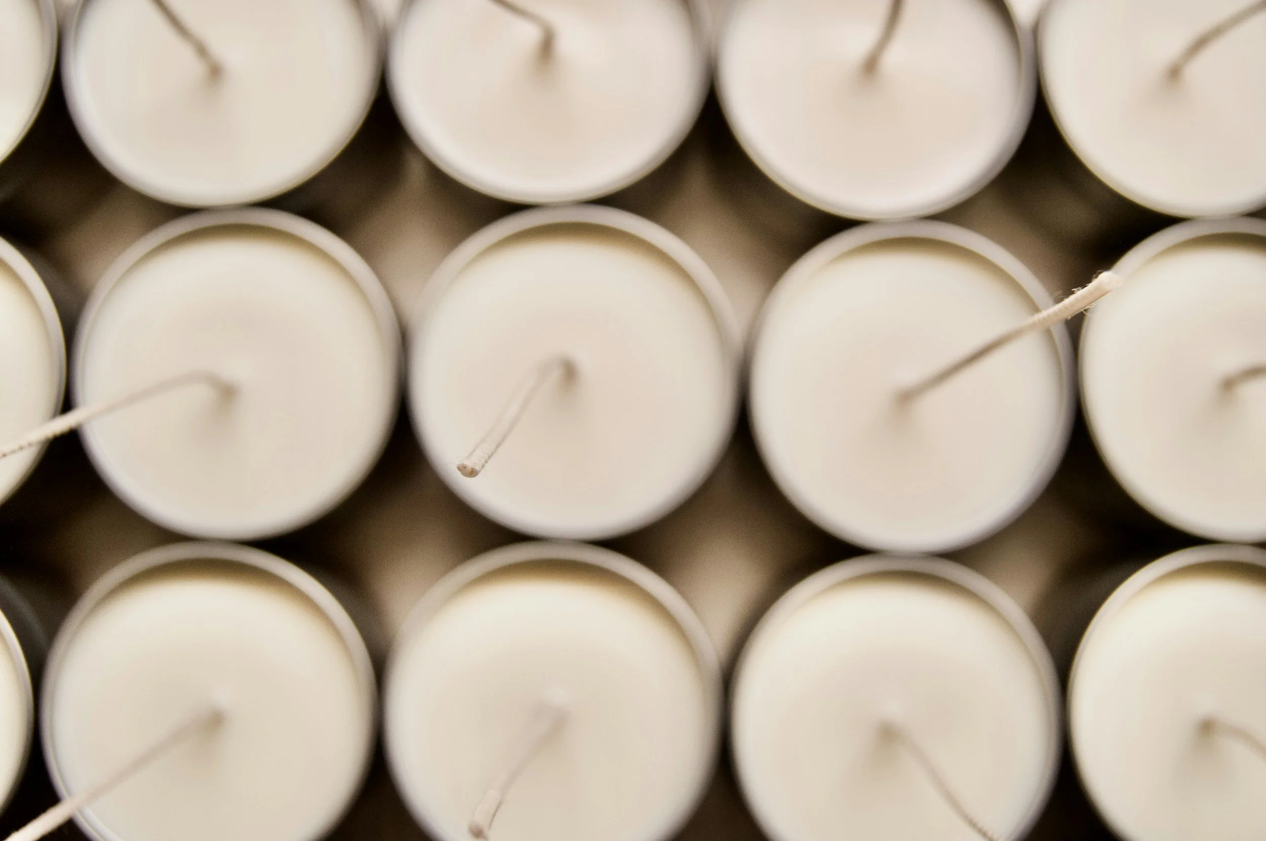 Close-up of multiple white candles arranged in a pattern with visible wicks.