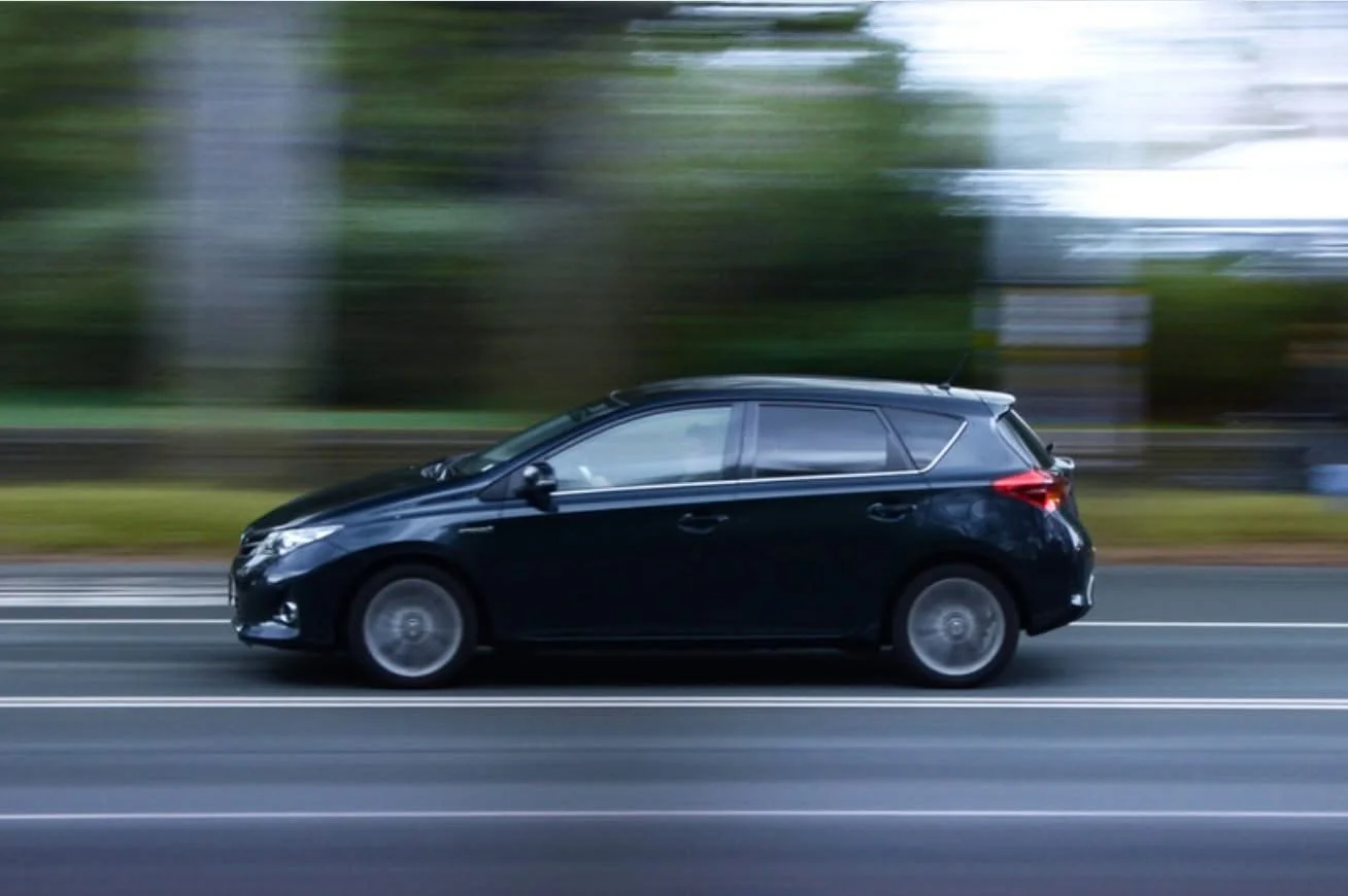 Voiture noire en mouvement sur une route avec un arrière-plan flou