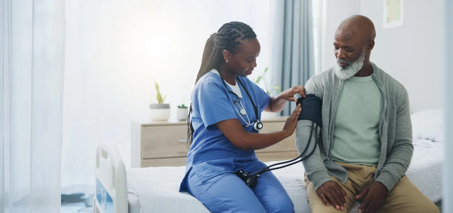 Nurse checking blood pressure of an elderly man in a hospital room.