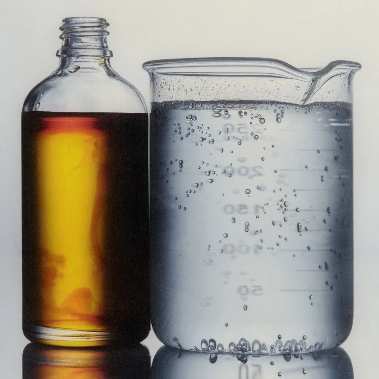 A glass jar filled with a dark liquid next to a measuring cup filled with bubbling clear water.