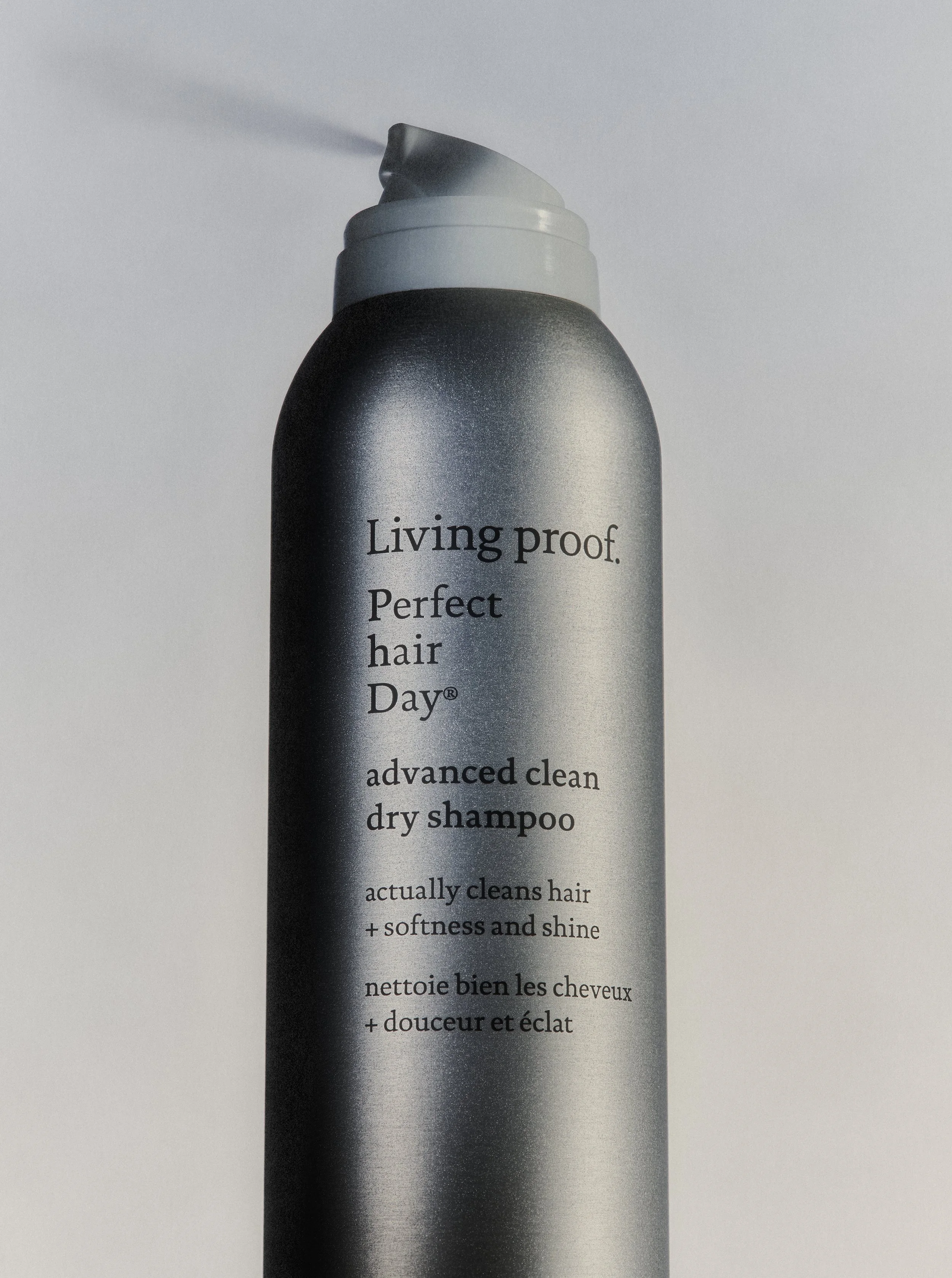 A can of dry shampoo labeled "Living proof. Perfect hair Day" with text describing its benefits for cleaning hair and adding softness and shine.