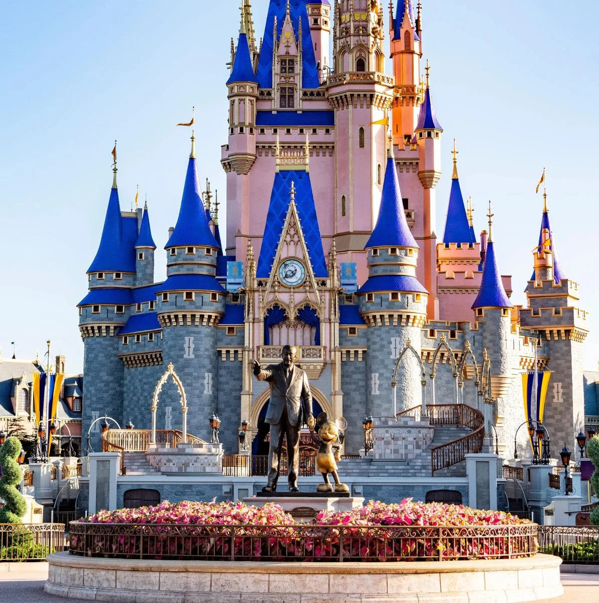 Cinderella Castle at Walt Disney World’s Magic Kingdom with the Walt Disney and Mickey Mouse statue in front.
