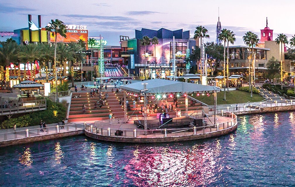 Universal CityWalk waterfront entertainment district with shops, restaurants, and a performance stage at dusk.