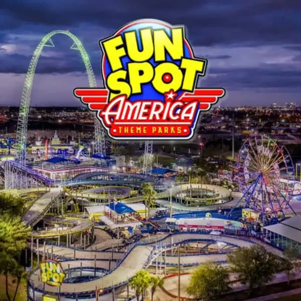 Fun Spot America Kissimmee at night with roller coasters, a Ferris wheel, and illuminated rides.