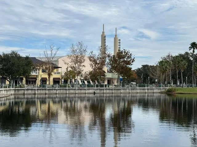 Celebration Town Center and Lake Rianhard waterfront with buildings, trees, and reflections on the lake.