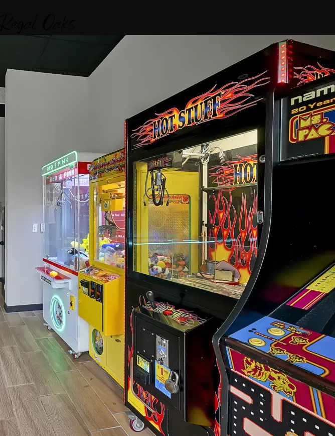 Arcade claw machines with colorful prizes inside, labeled 'Hot Stuff' and other game titles, located in an indoor entertainment center.