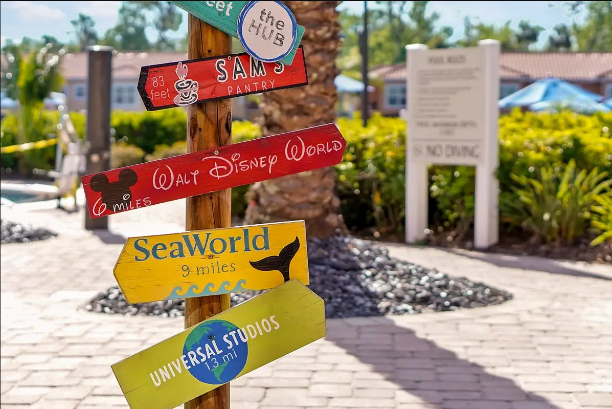 Colorful directional signs pointing to various attractions including Walt Disney World, SeaWorld, universal studios, and Sam's Pantry.