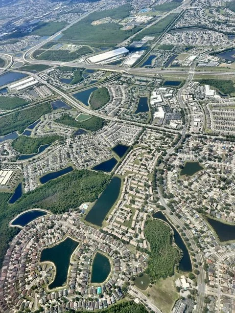 Aerial view of a suburban area with lakes, residential neighborhoods, and highways.