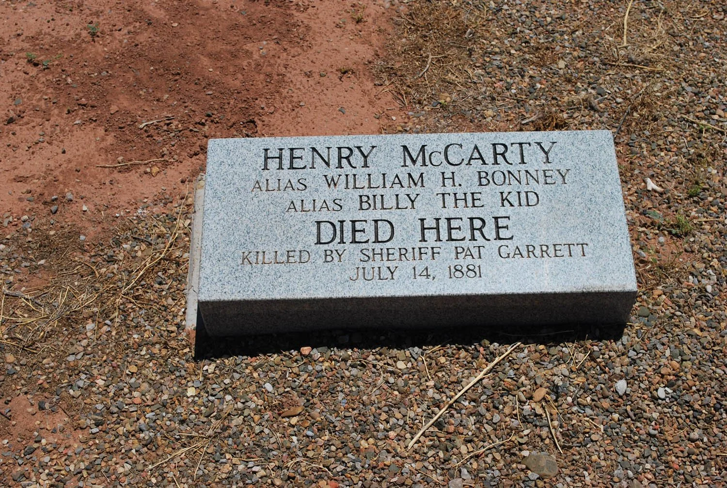 A gravestone with the inscription 'Henry McCarty, alias William H. Bonney, alias Billy the Kid, died here, killed by Sheriff Pat Garrett, July 14, 1881'
