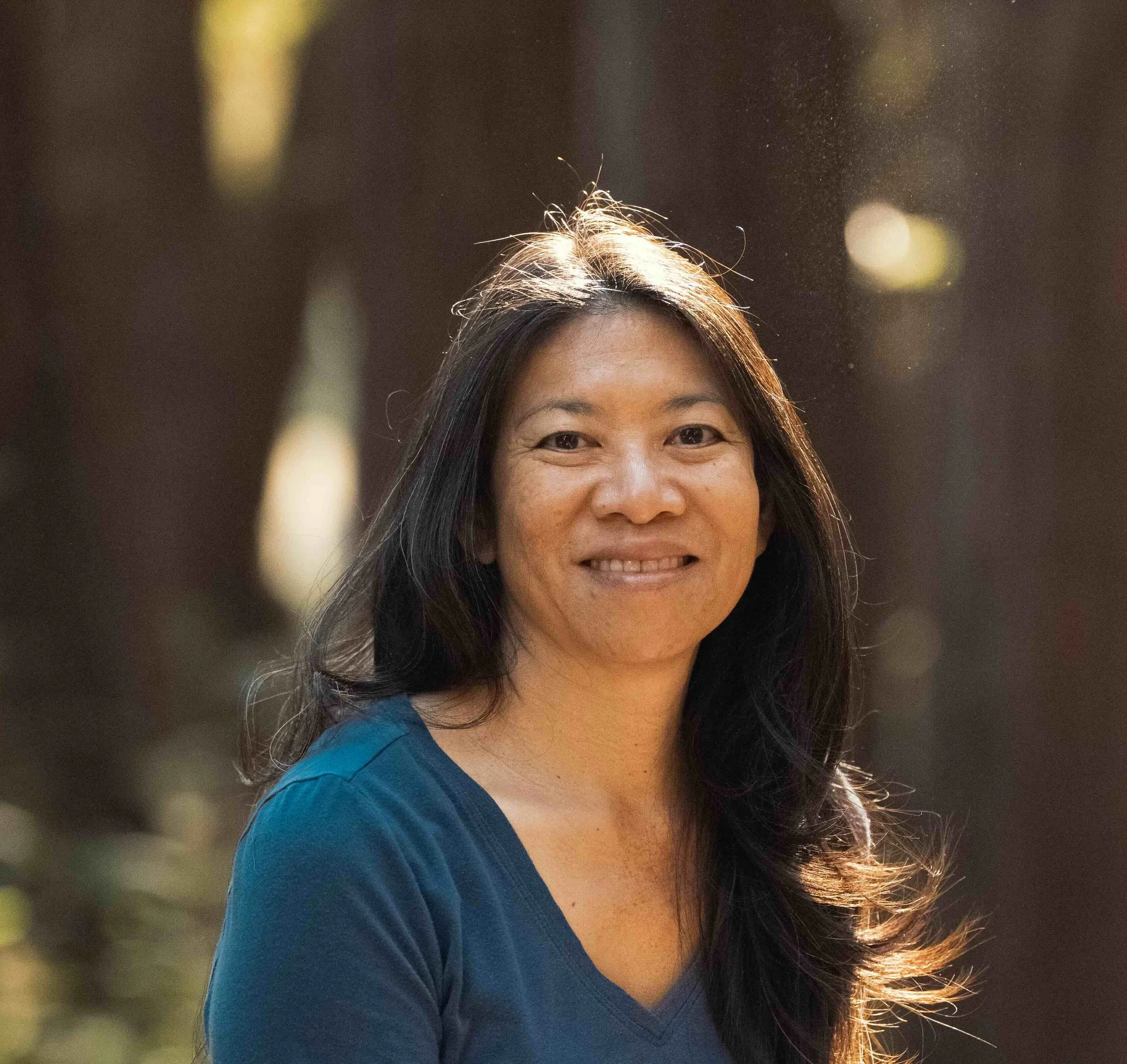 Close-up of a smiling woman with dark hair wearing a blue top, who provides IOLTA three-way reconciliation.