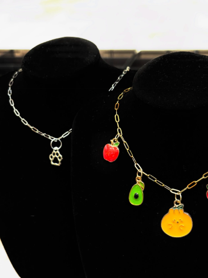Two jewelry displays featuring colorful fruit shaped pendant necklaces.