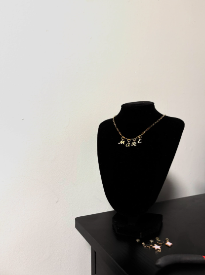 Gold necklace displayed on a black jewelry bust.