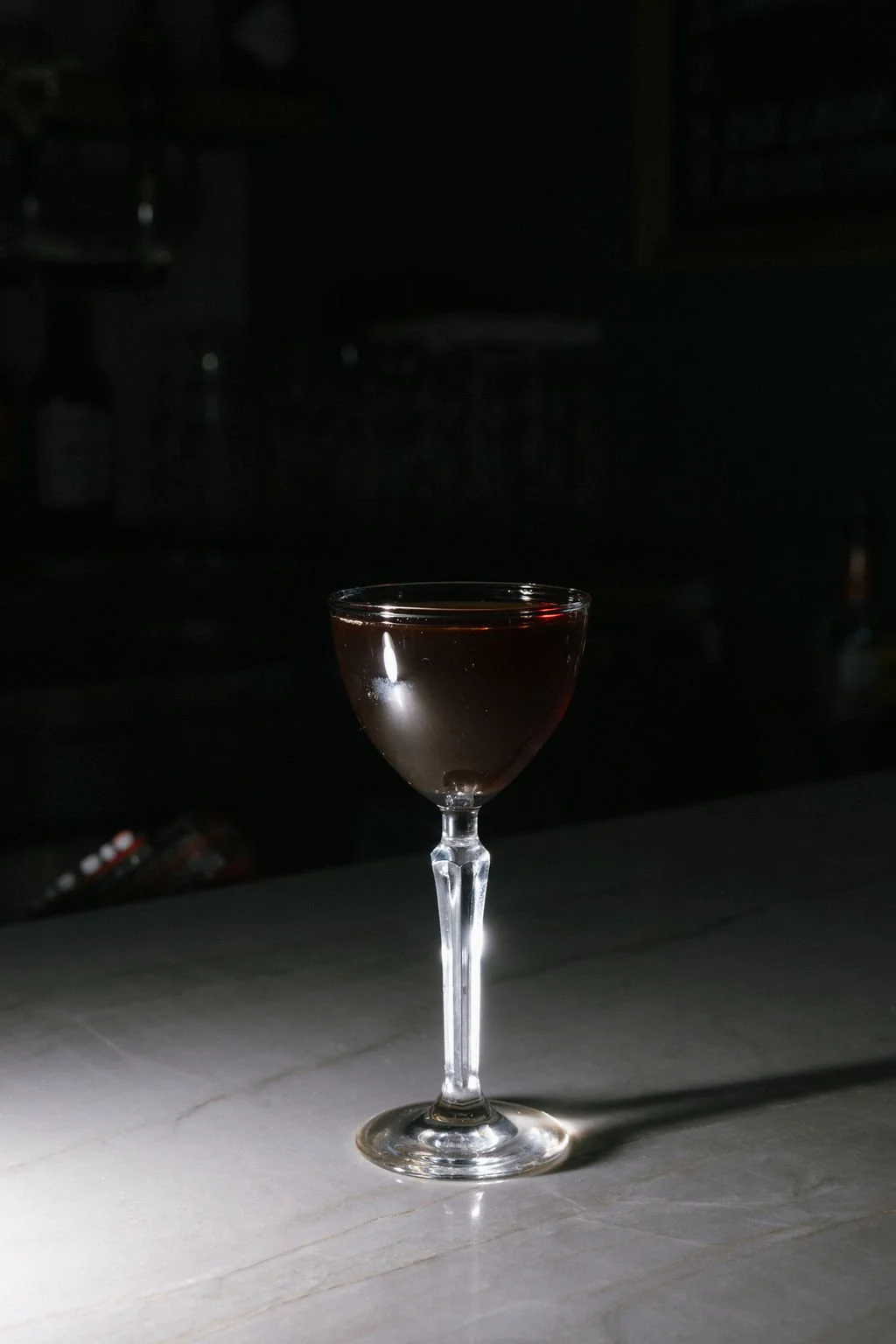 A glass of red wine on a white marble surface with a dark background.