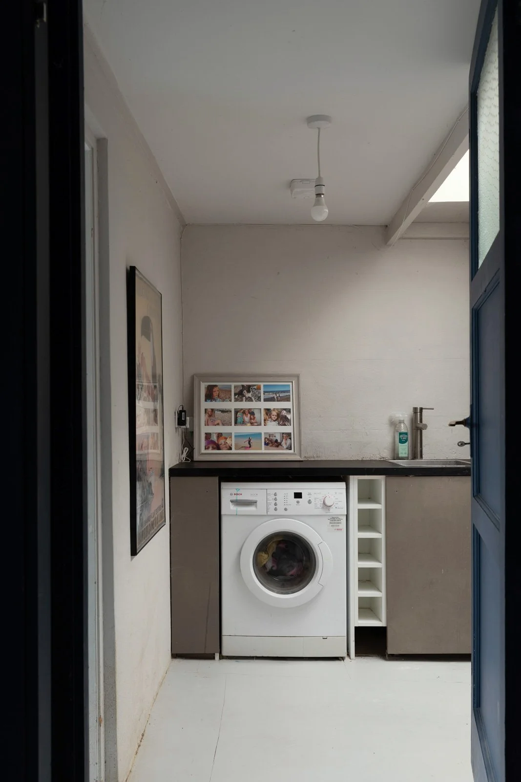Laundry room with a washing machine, framed photo collage, soap dispenser, sink, and a picture on the wall.