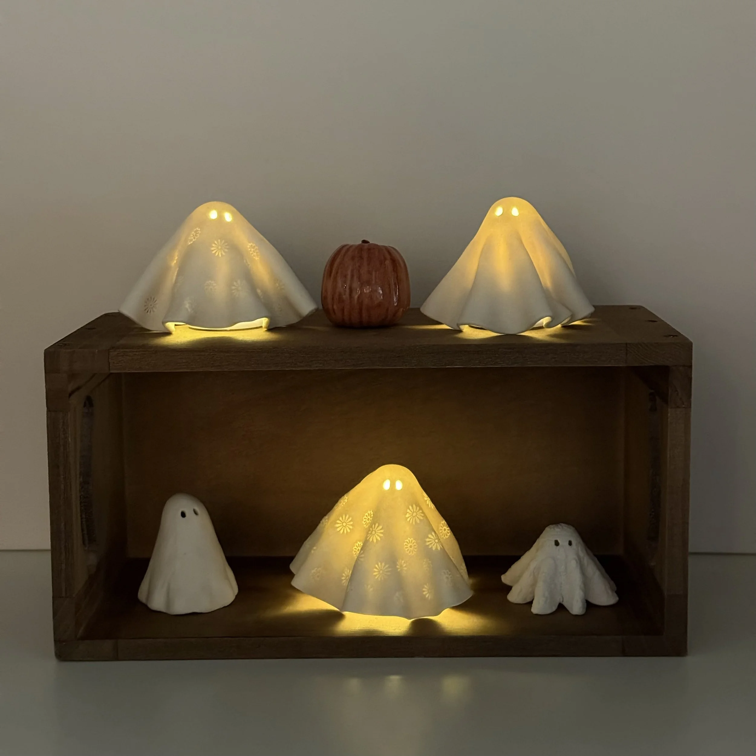 Decorative lamps shaped like ghosts and a pumpkin on a wooden table.