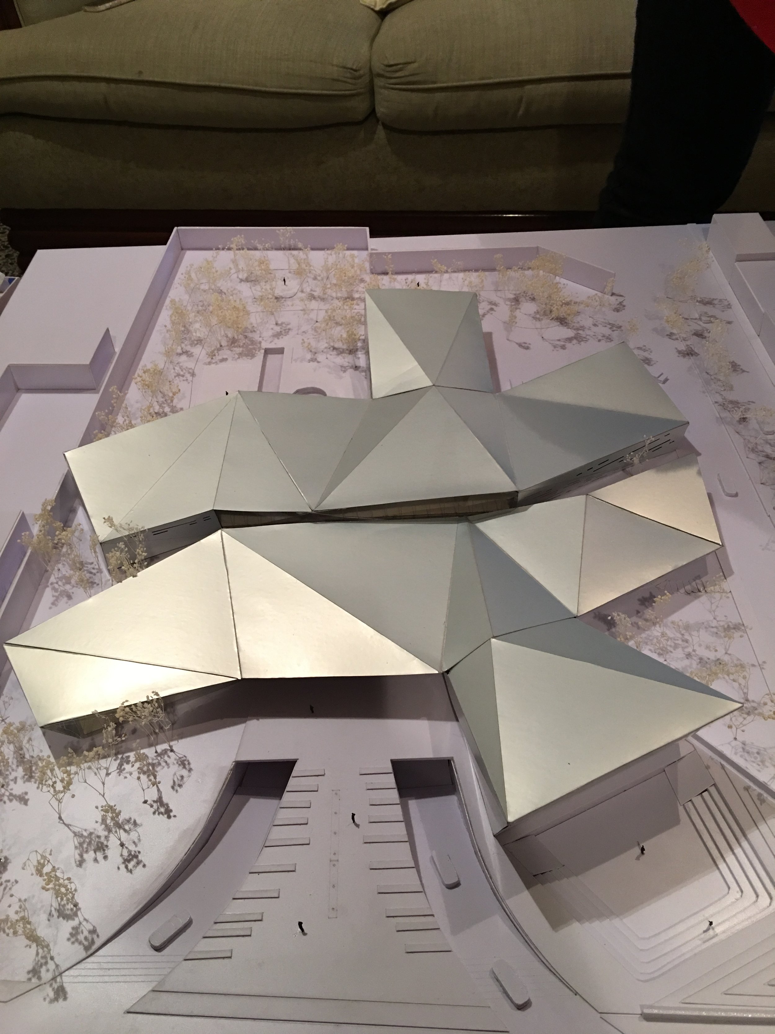 Modelo a escala de un diseño arquitectónico de un edificio con techos en forma de punte agudo, paredes blancas y espacio para árboles o áreas verdes.