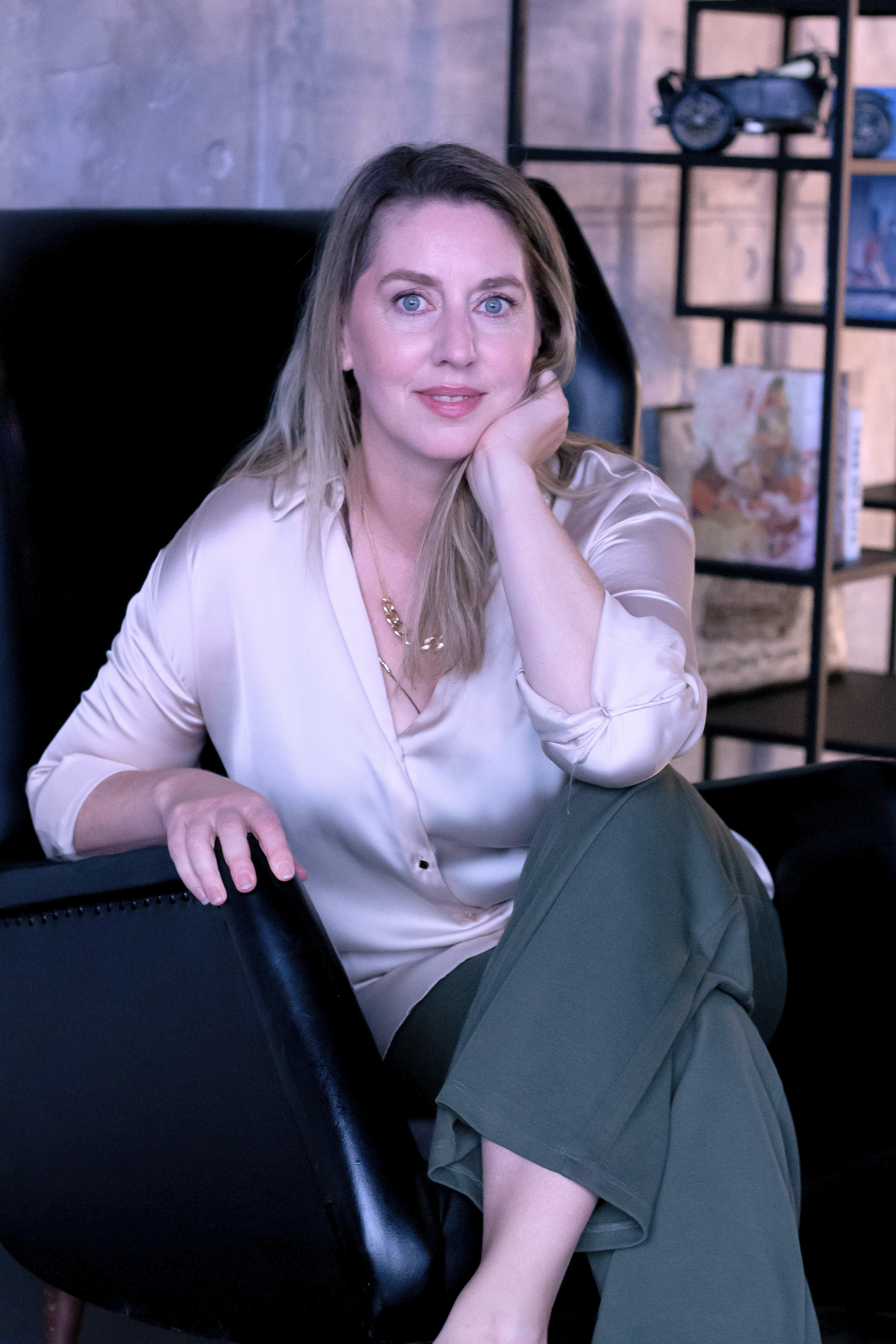 Woman in a white blouse sitting on a sofa with her hand resting on her cheek