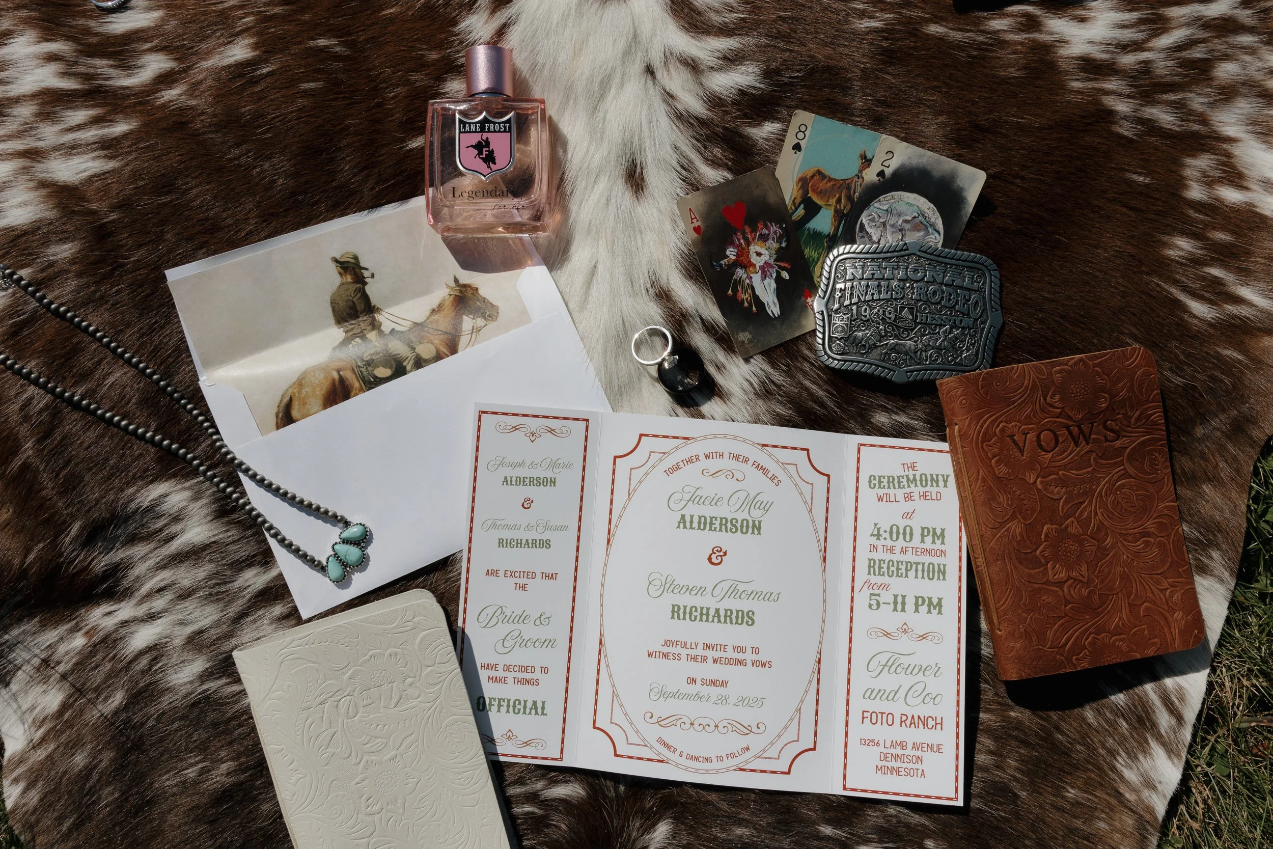 Wedding invitation, playing cards, perfume bottle, ring, necklace, decorative box, leather journal, and a photograph of a person riding a horse on a horse fur background.