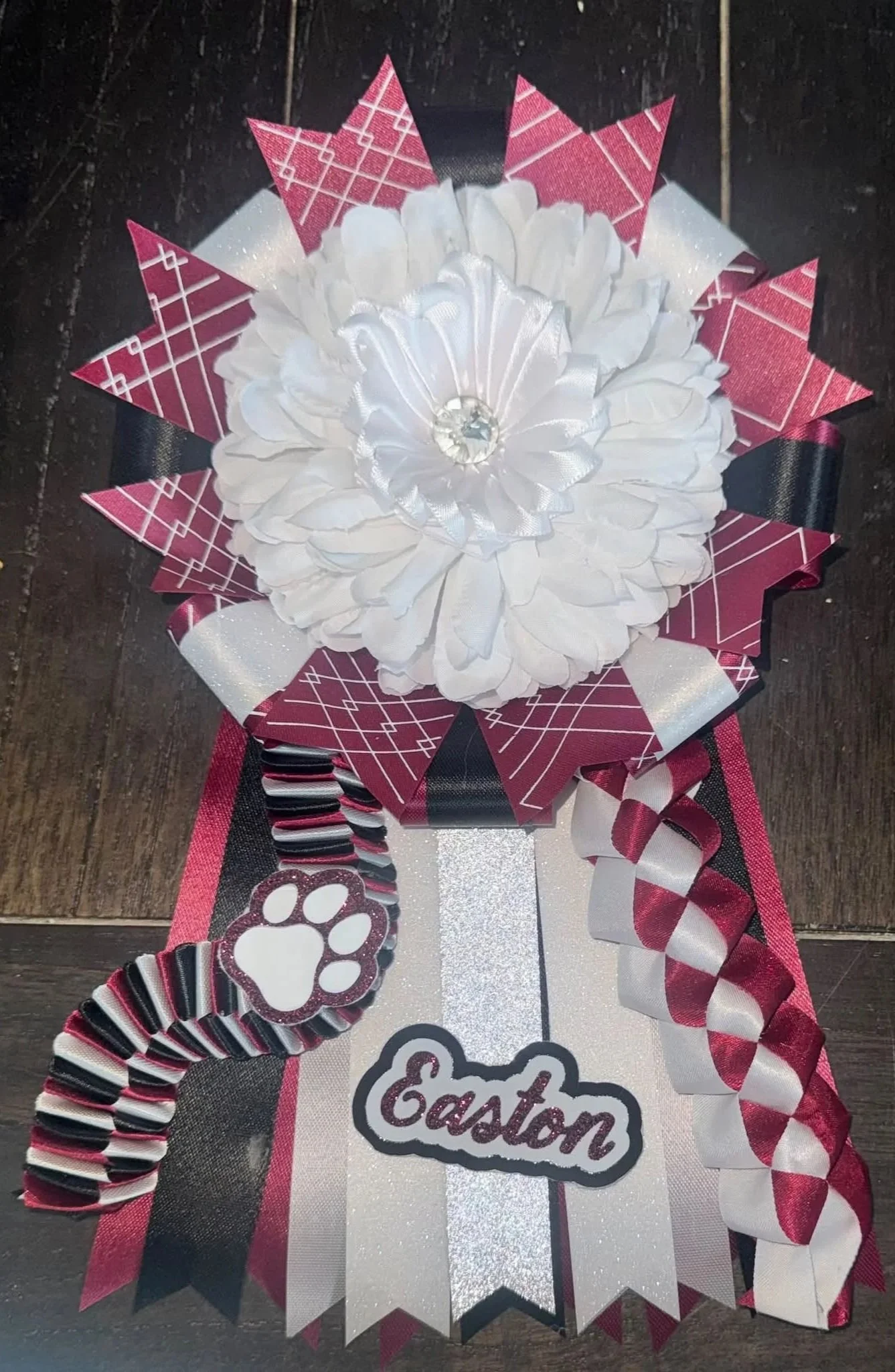 Decorative ribbon and bow with an Easter theme, featuring a large white satin flower, red and black plaid ribbon, paw print ribbon, and a sign that says 'Easter'.