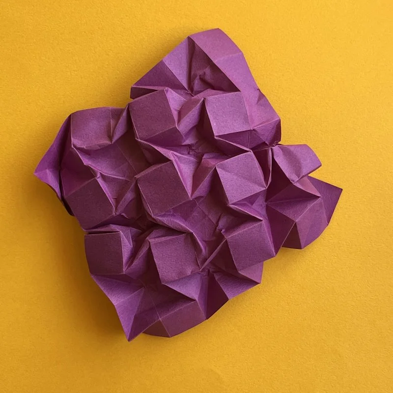 Purple crumpled sheet of paper on a yellow background.