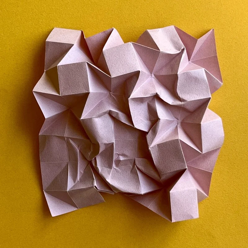 Crumpled pink piece of paper on a yellow background.