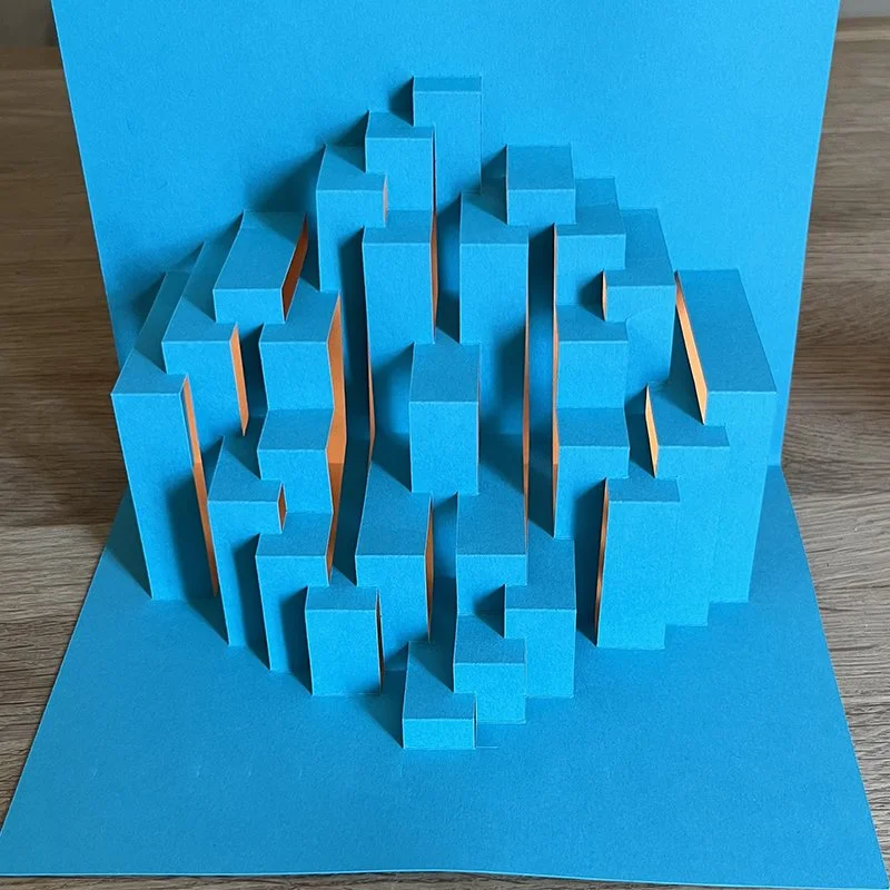 3D blue paper art with vertical rectangular cutouts on a blue background, creating a geometric pattern.