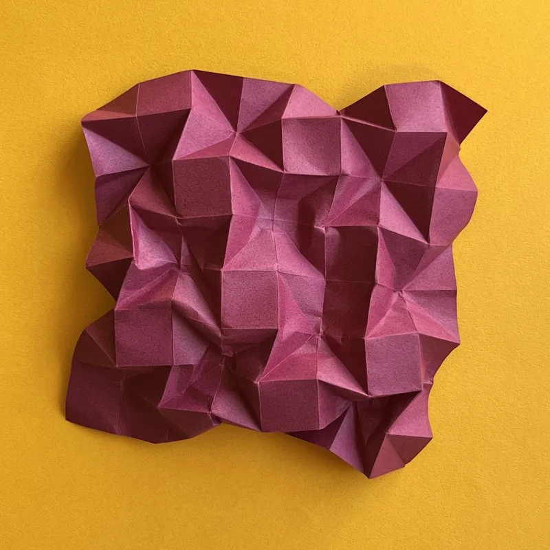 Crumpled pink paper against a yellow background.