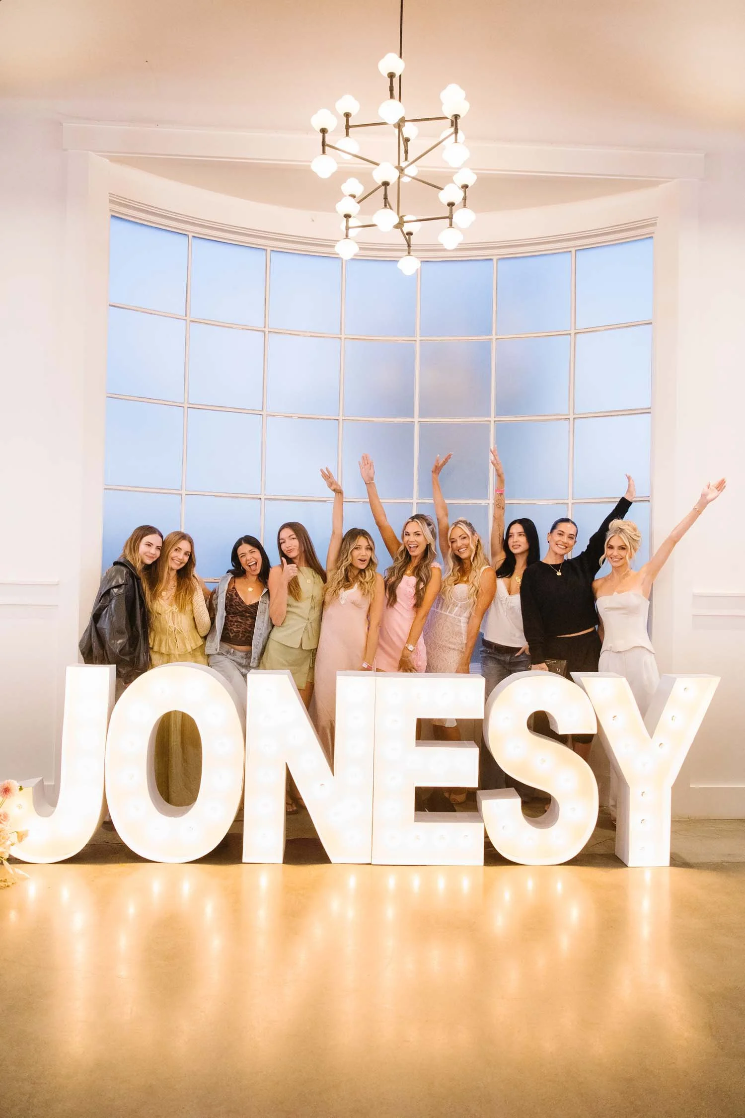 A group of women standing behind a light up JONESY sign