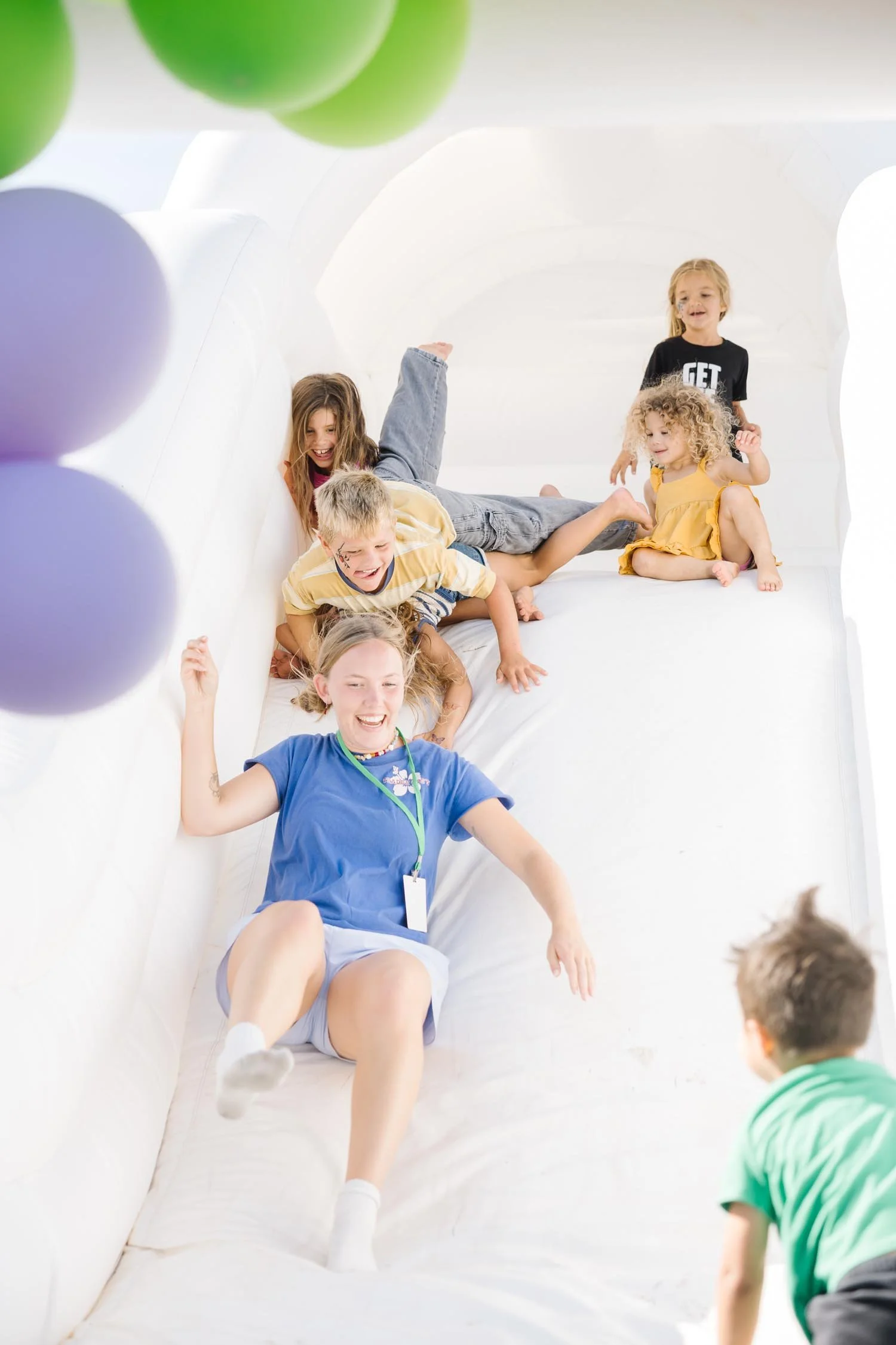 A group of kids playing and sliding down an inflatable slide