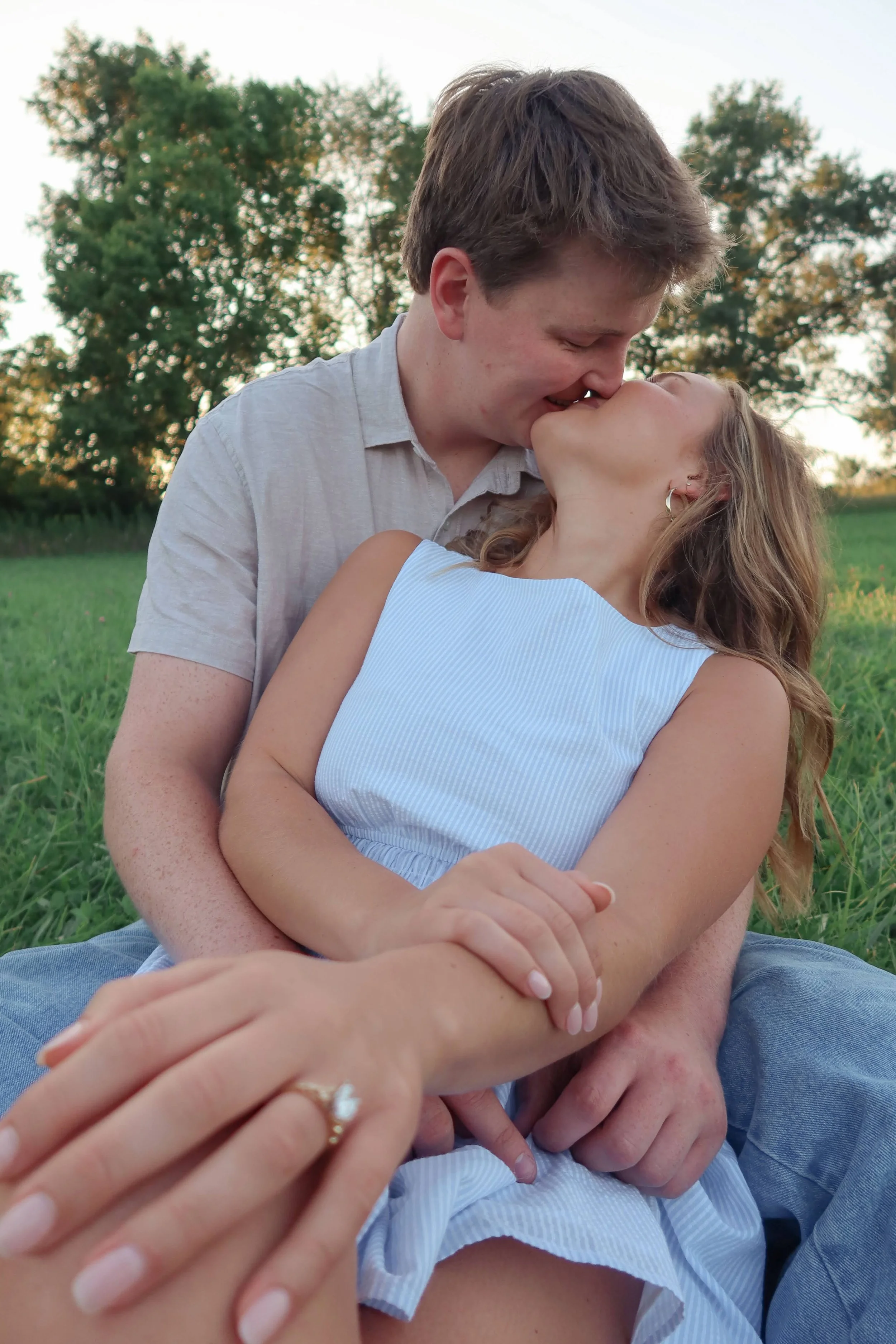 A young couple shares a kiss outdoors in a park,