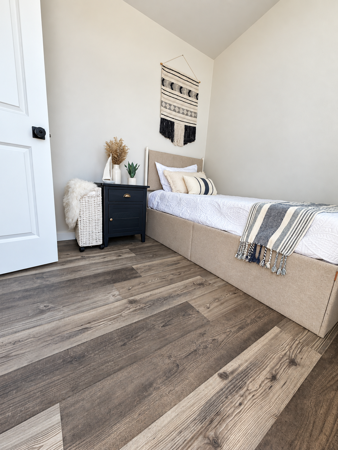 Next, open the second interior photo—the bedroom and paste this into Image Alt Text: Forever 40-foot 2B bedroom with a bed, striped bedding, dark bedside cabinet, and woven wall hanging.