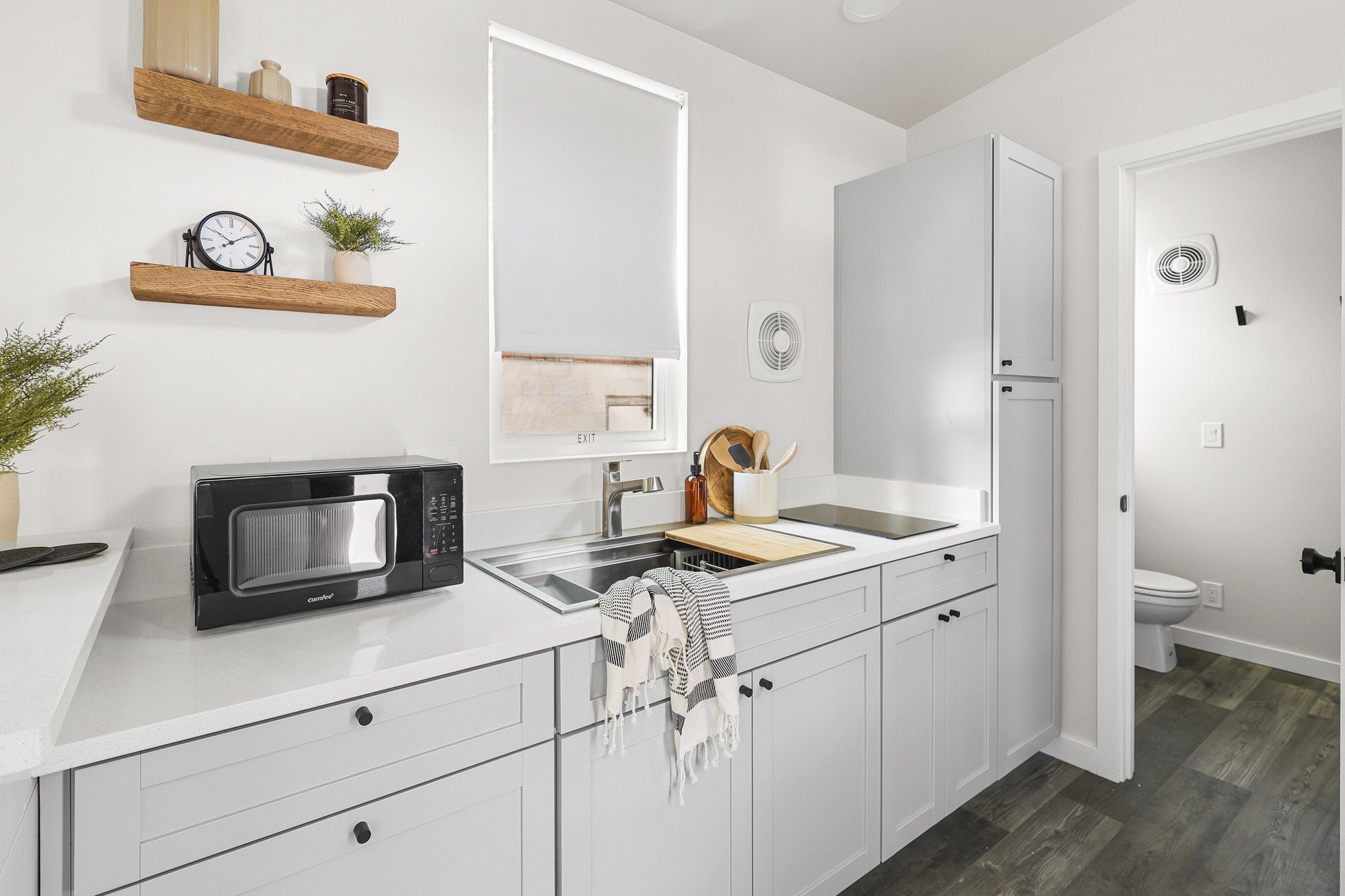Forever 24-foot Studio kitchen with light cabinets, a quartz countertop, stainless steel sink beneath a window, cooktop.