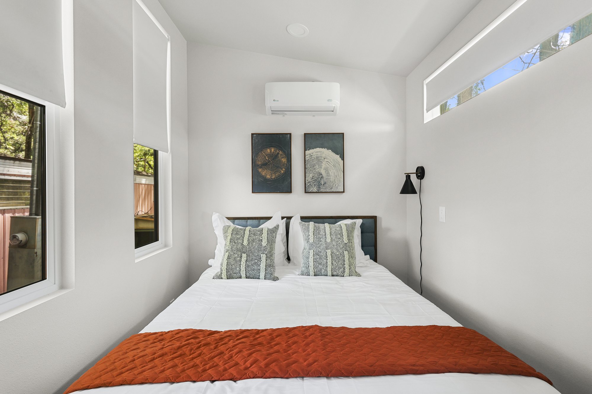Forever 24-foot Studio sleeping area with a bed, tall windows, a high horizontal window, and a wall-mounted mini-split.