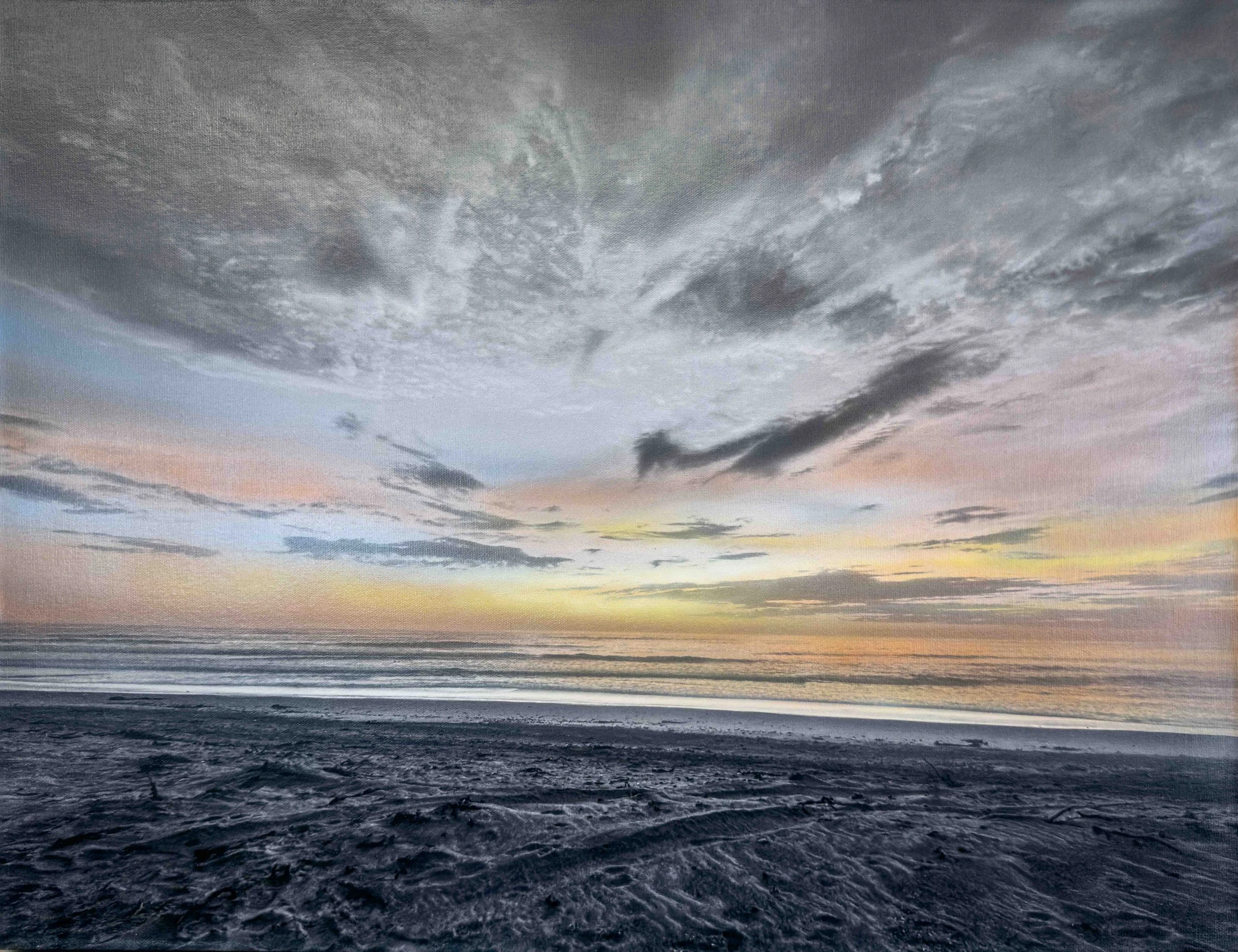 A view of a dark ocean under a cloudy sky during sunset.