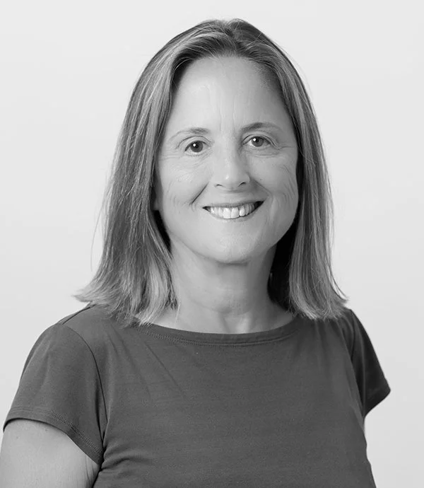 Portrait of a smiling woman with shoulder-length hair and a plain t-shirt, in black and white.