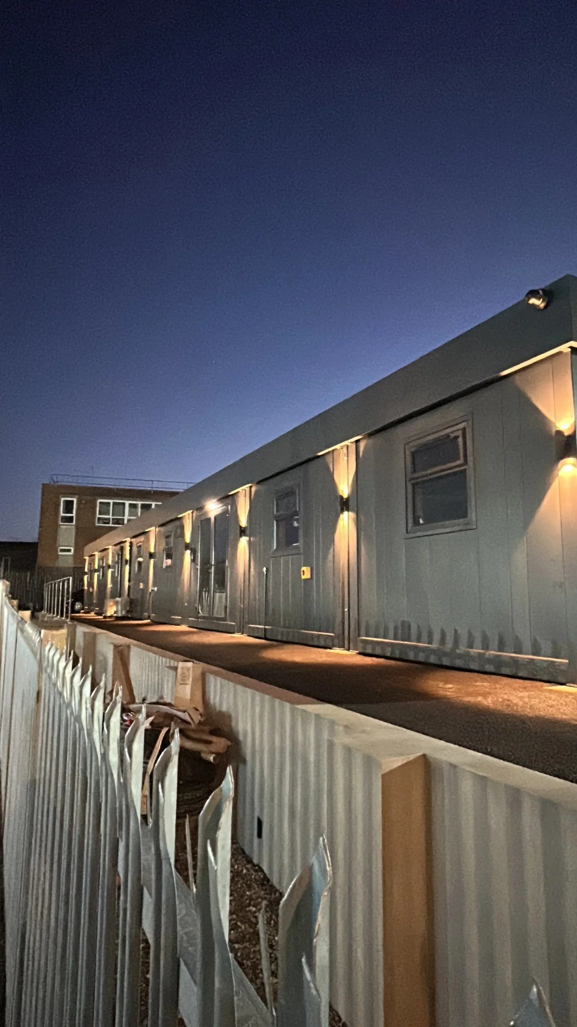 External wall lights installed on site cabins at dusk by Severn & Shires Electrical