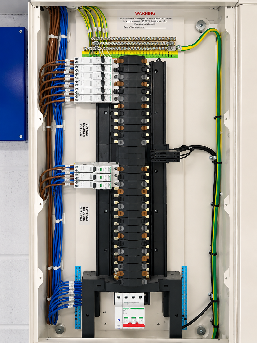 Electrical breaker panel with multiple switches, wires, and labels inside a white metal enclosure.