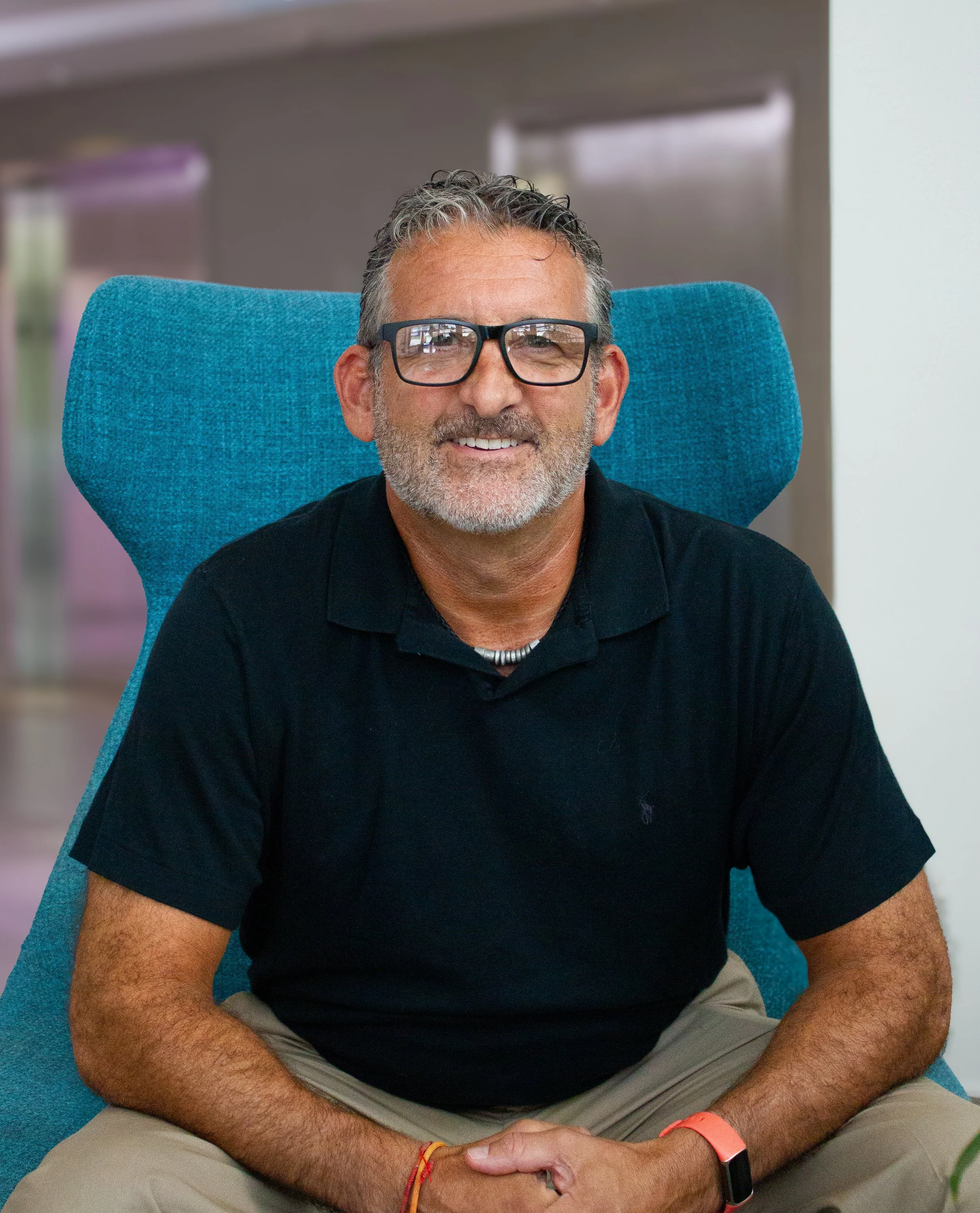 Jon Pollack, long-term care insurance specialist headshot sitting in a blue chair