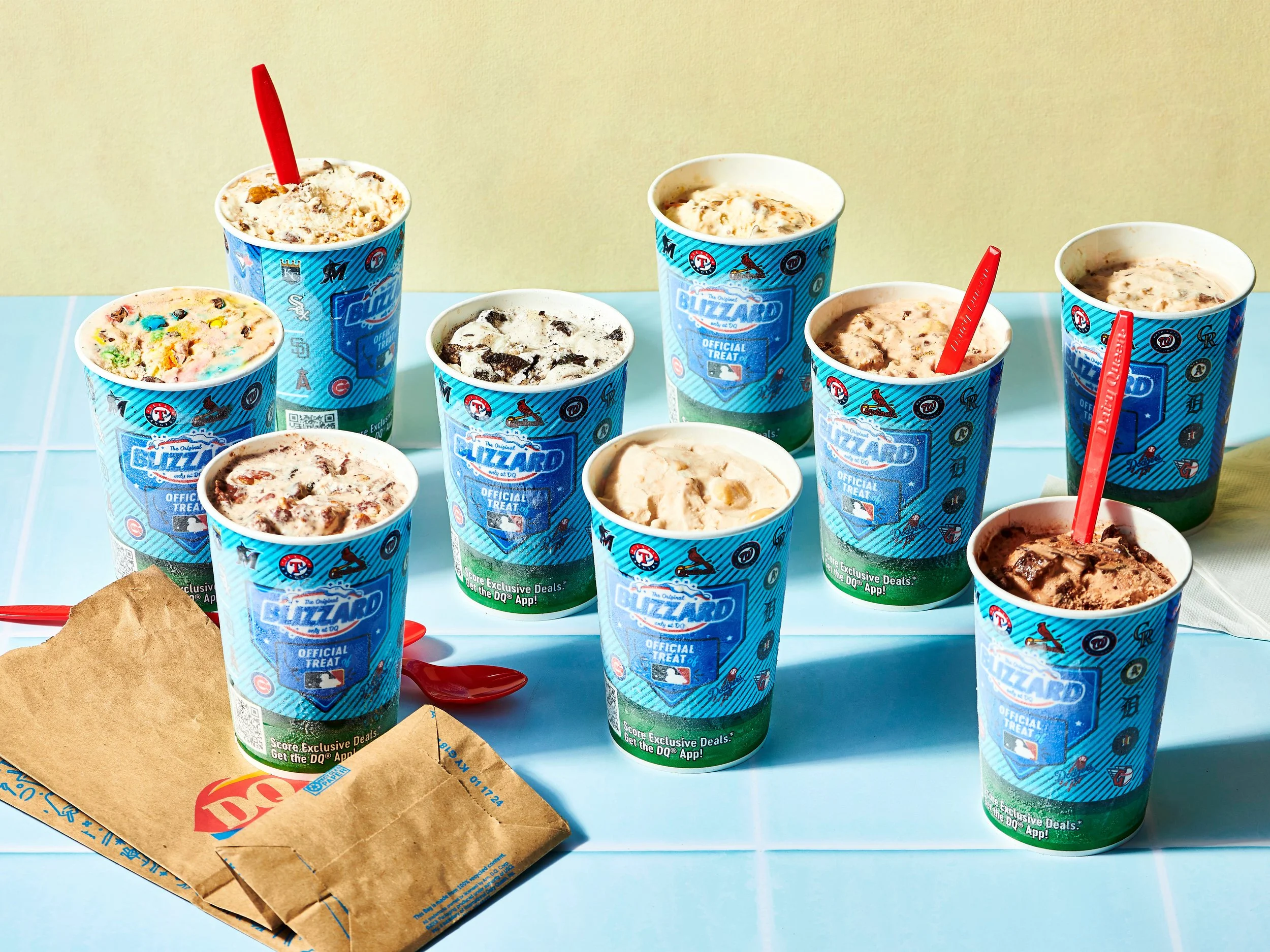 Several cups of ice cream with various flavors and toppings arranged on a light blue tray, with a McDonald's paper bag and receipts nearby.