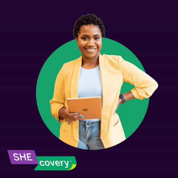 A confident woman with natural short curly hair smiling, holding a tablet, wearing a yellow blazer over a light blue top, standing against a dark purple background with a green circle behind her, and a purple and green "Shecovery" logo at the bottom left corner.