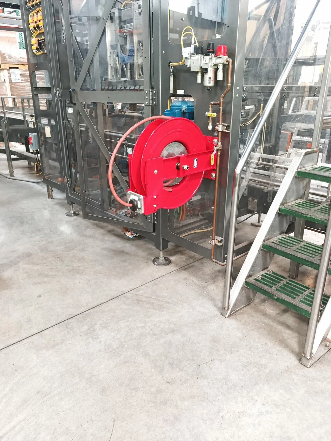 Red air hose reel installed on industrial equipment beside the compressed air lines