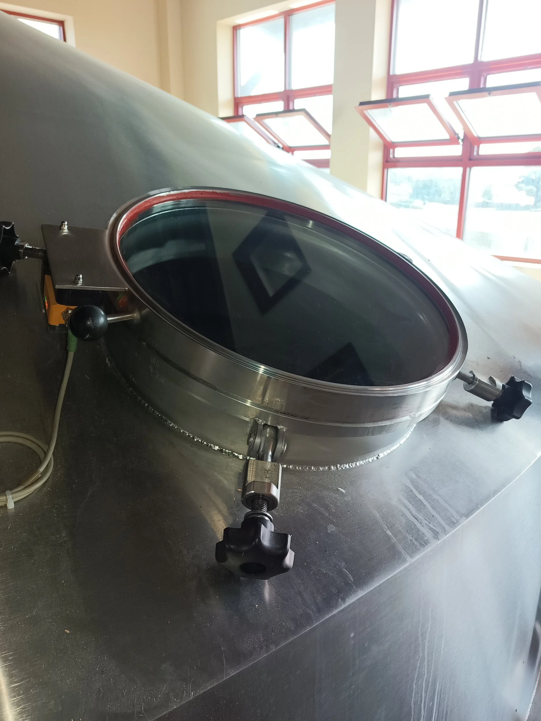 Tempered glass panel installed in the round access door of a food-grade stainless steel lauter tun