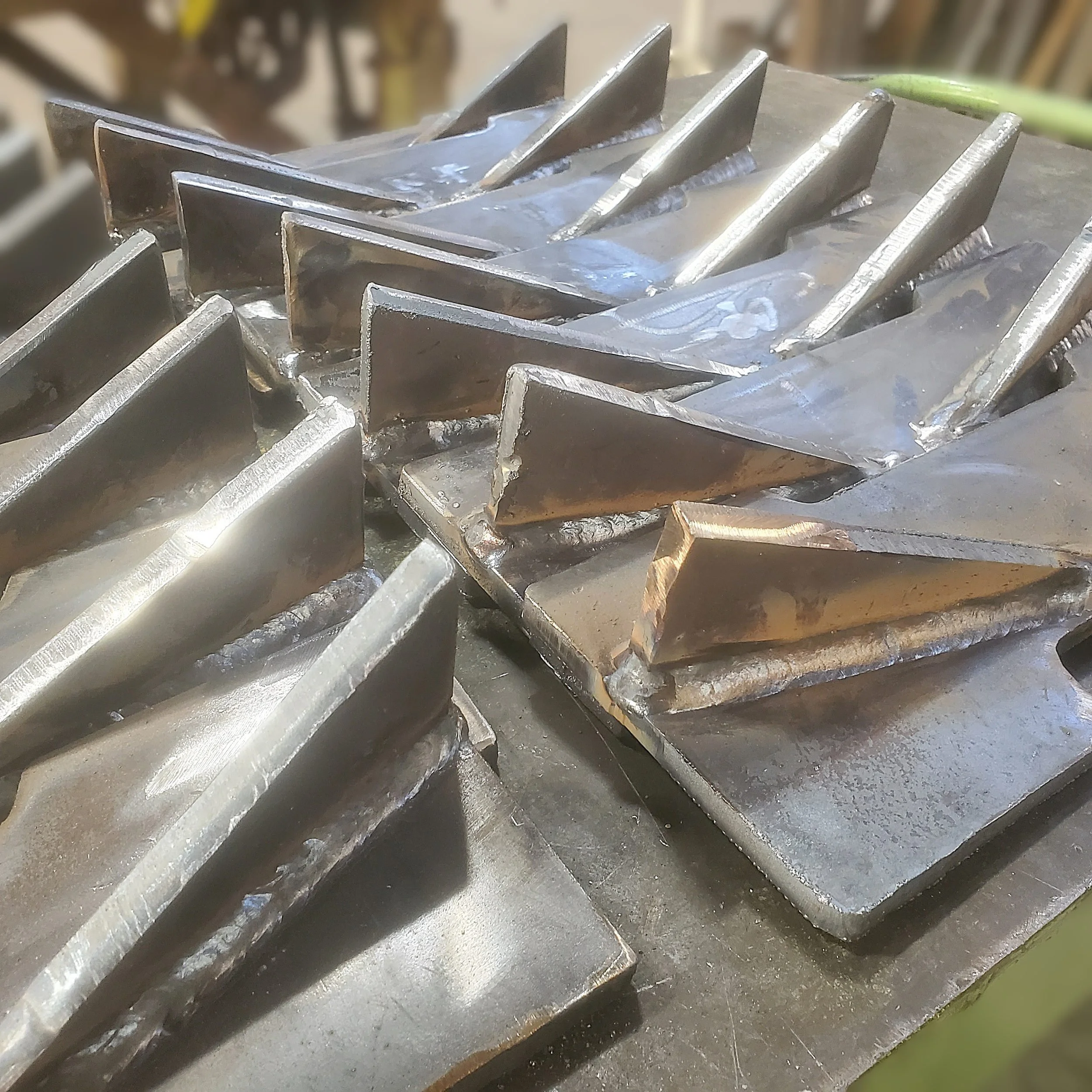 Rows of fabricated and welded steel conveyor teeth for a lumber mill debarker