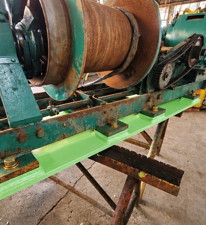 Custom winch support base, painted green, bolted under an industrial winch with an exposed chain drive