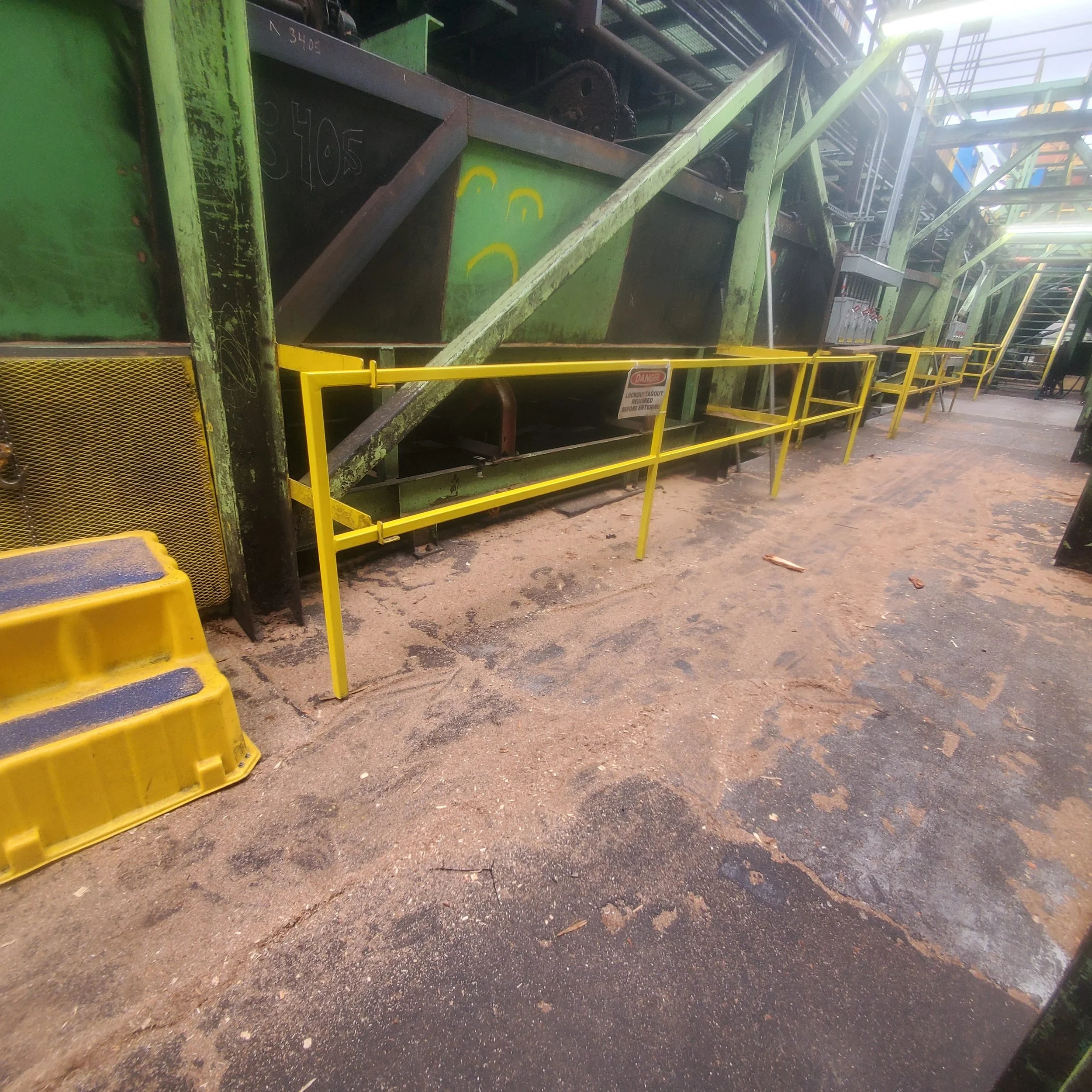 Yellow steel safety railing along an industrial plant walkway