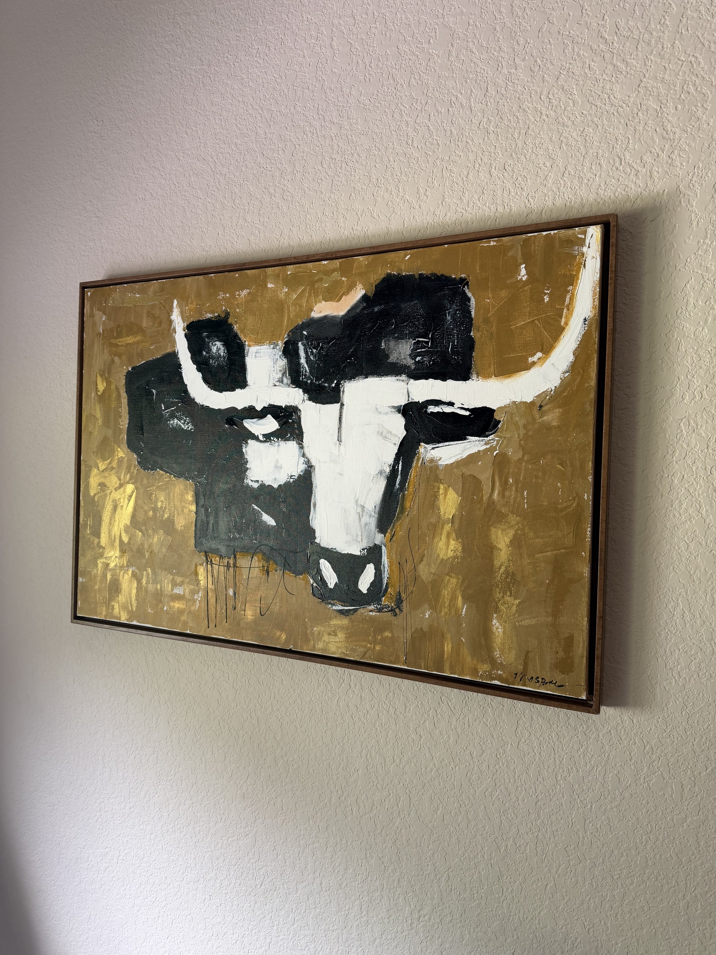 Abstract painting of a cow's head, primarily in black and white, on a gold background, signed in the bottom right corner.